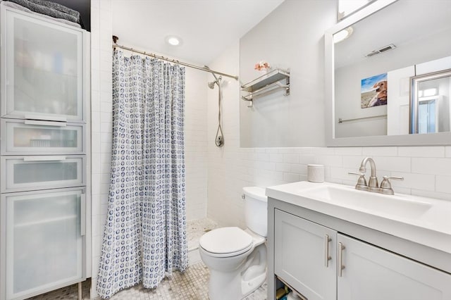 bathroom with walk in shower, vanity, tile walls, and toilet