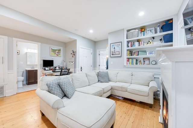 living room featuring built in features and light hardwood / wood-style flooring