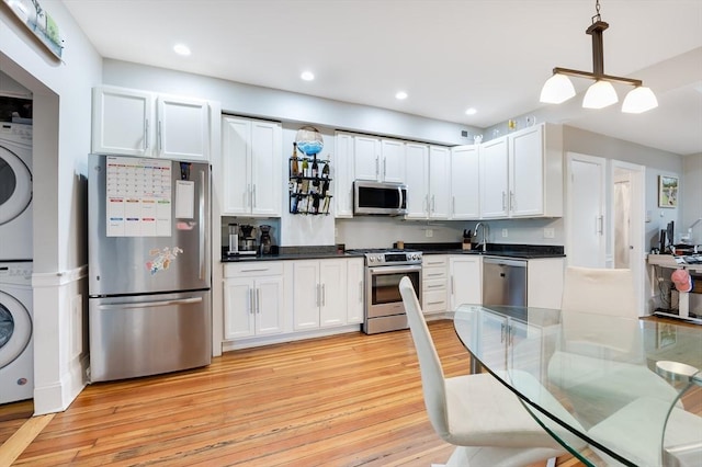 kitchen with stacked washer / dryer, white cabinets, pendant lighting, and appliances with stainless steel finishes