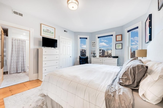 bedroom featuring ensuite bath and light wood-type flooring