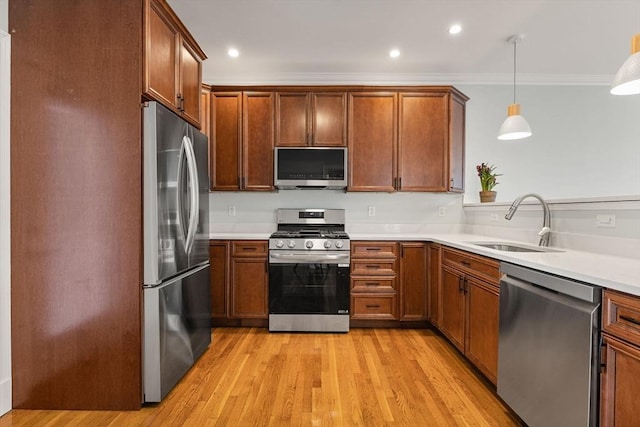kitchen with crown molding, a sink, light countertops, light wood-style flooring, and stainless steel appliances