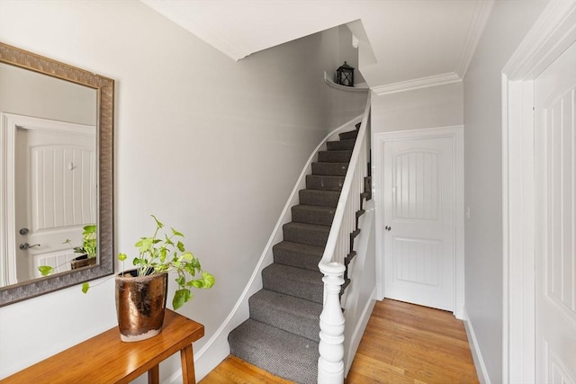 staircase featuring crown molding, baseboards, and wood finished floors