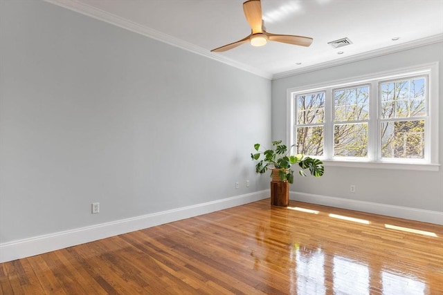 empty room with baseboards, ornamental molding, wood finished floors, and visible vents