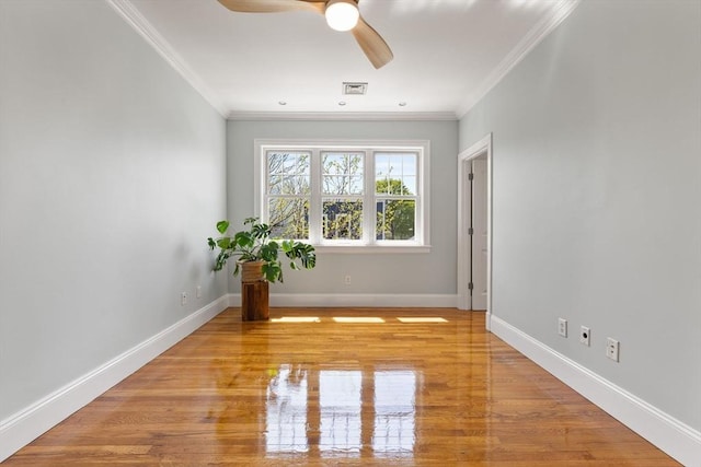 spare room with crown molding, baseboards, a ceiling fan, and visible vents