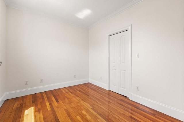 spare room with baseboards, ornamental molding, and hardwood / wood-style flooring