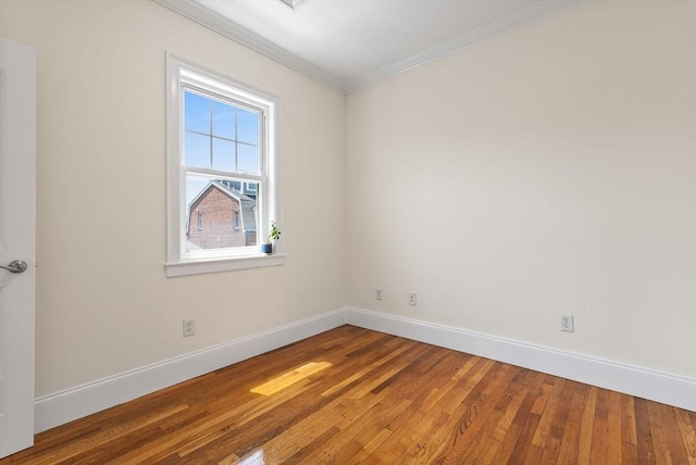 empty room featuring crown molding, baseboards, and wood finished floors