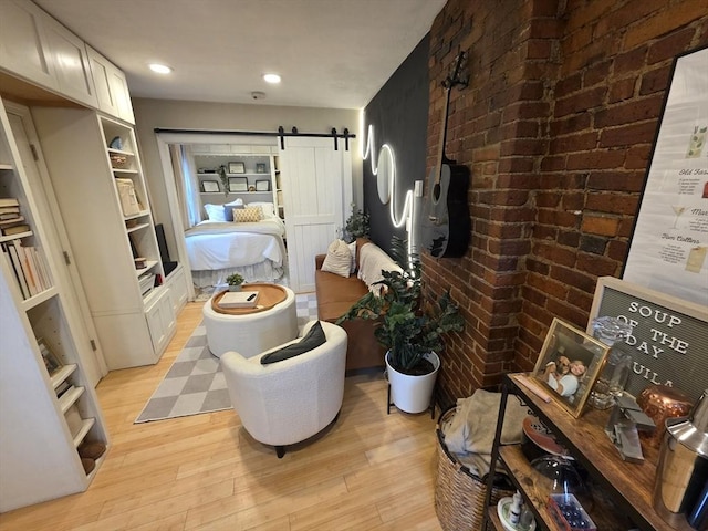 corridor with light wood-style flooring, brick wall, a barn door, built in features, and recessed lighting