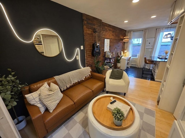 living room with wood finished floors, brick wall, and recessed lighting