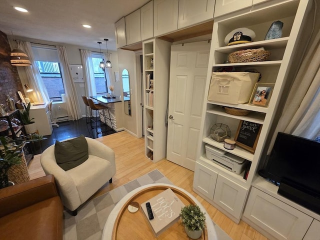 living area featuring light wood-type flooring, recessed lighting, and a baseboard heating unit