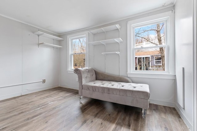 sitting room with crown molding, baseboards, and wood finished floors