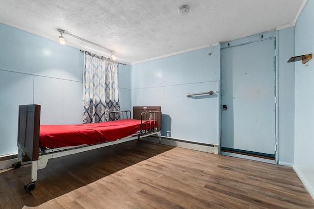 bedroom with baseboards, a textured ceiling, and wood finished floors
