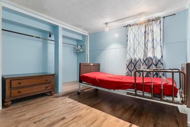 bedroom featuring a textured ceiling, track lighting, and wood finished floors