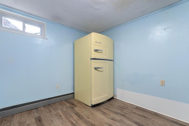 below grade area featuring a textured ceiling, wood finished floors, and refrigerator