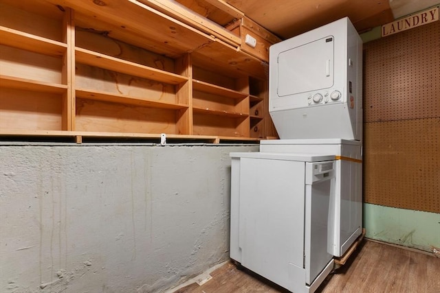 laundry area with wood finished floors and stacked washer / dryer