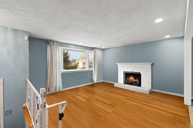 42 Mary Anne Ave, Brockton, MA 02302 - unfurnished living room featuring wood finished floors, a textured ceiling, a brick fireplace, and recessed lighting