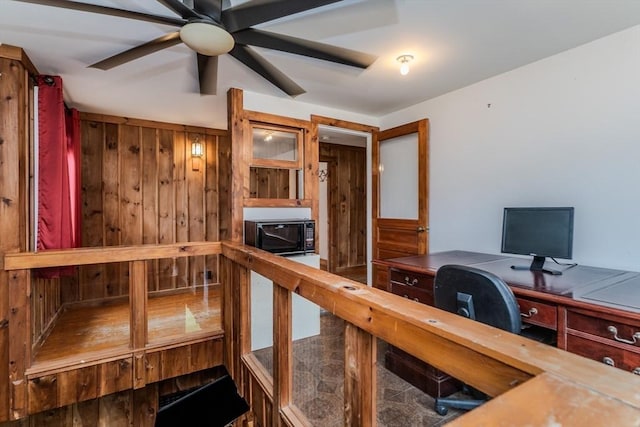 home office featuring ceiling fan and wood walls