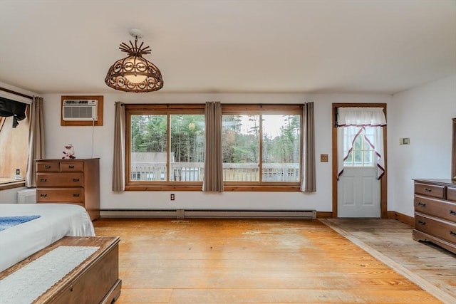 bedroom with light hardwood / wood-style floors, a wall unit AC, and a baseboard heating unit