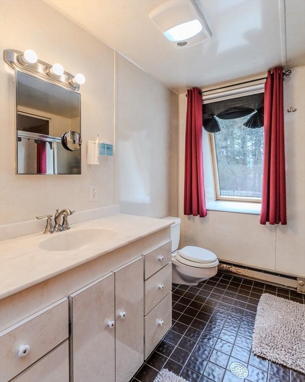 bathroom featuring baseboard heating, vanity, toilet, and tile patterned flooring