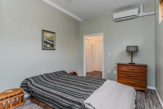 bedroom with wood-type flooring and an AC wall unit