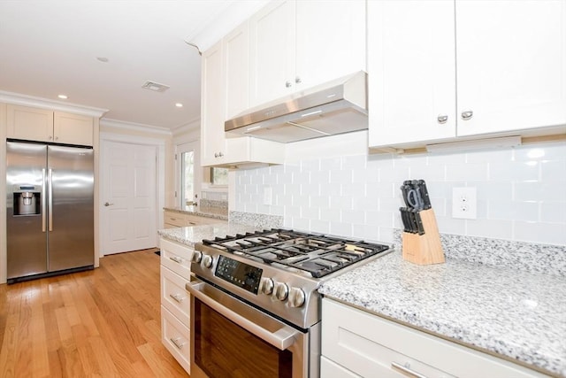 kitchen featuring under cabinet range hood, visible vents, appliances with stainless steel finishes, and light stone counters