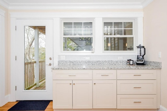 bar featuring light wood-type flooring, crown molding, and decorative backsplash