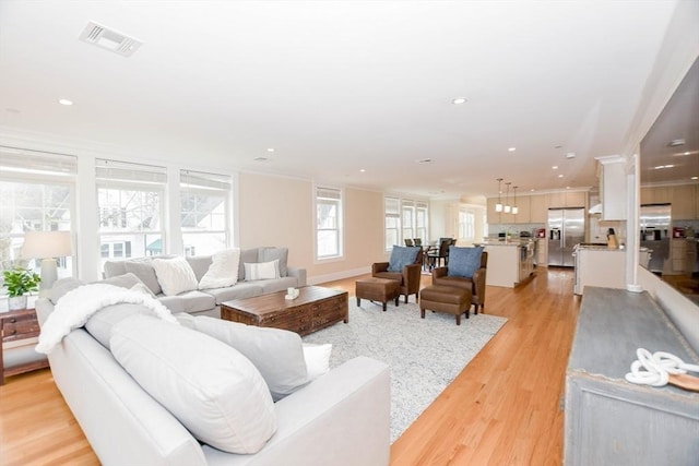 living room with crown molding, recessed lighting, visible vents, and light wood-style floors