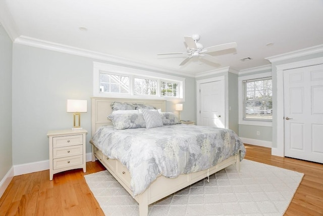 bedroom with light wood finished floors, baseboards, visible vents, and ornamental molding