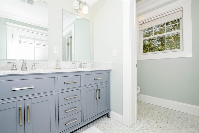 full bath featuring double vanity, baseboards, toilet, and a sink