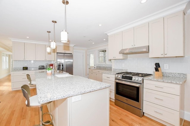 kitchen with pendant lighting, a center island with sink, stainless steel appliances, white cabinets, and under cabinet range hood