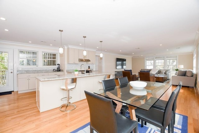 dining space with light wood-style floors, a wealth of natural light, crown molding, and recessed lighting