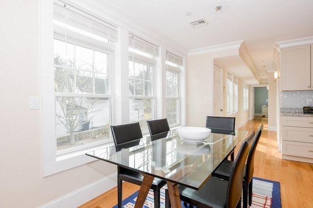 dining space with visible vents, baseboards, light wood-style flooring, and crown molding