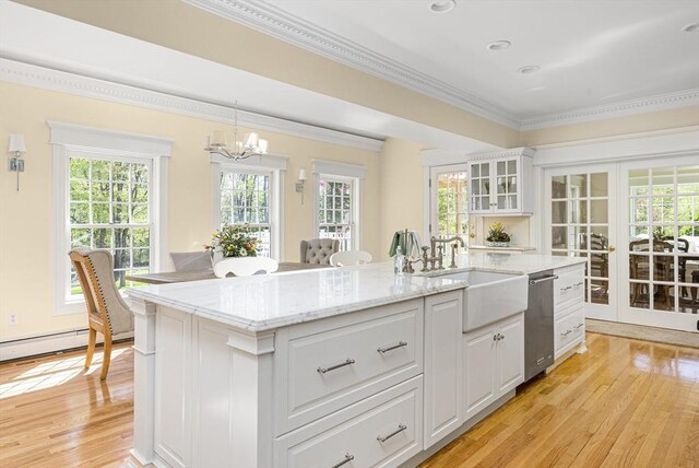 kitchen featuring decorative light fixtures, a center island with sink, light hardwood / wood-style flooring, and stainless steel dishwasher