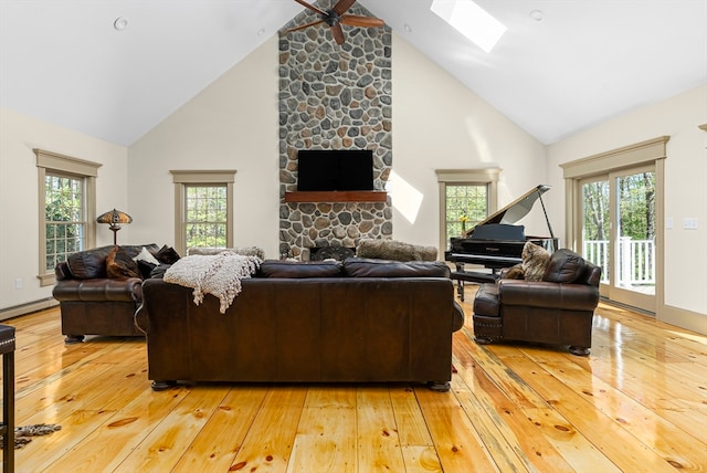 living room with a stone fireplace, high vaulted ceiling, wood-type flooring, and plenty of natural light