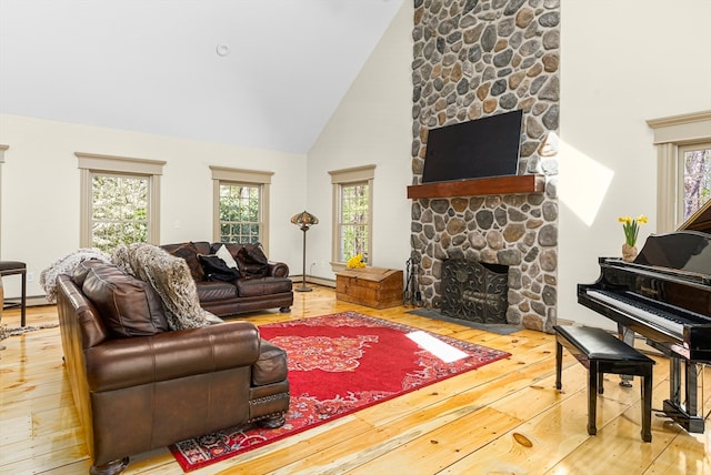 living room featuring high vaulted ceiling, a fireplace, and light wood-type flooring