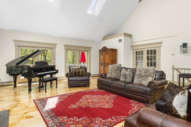 living room featuring a healthy amount of sunlight, high vaulted ceiling, a skylight, and hardwood / wood-style floors