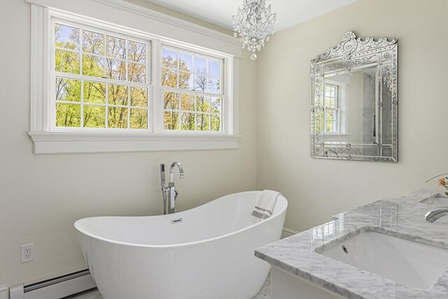 bathroom with an inviting chandelier, a bath to relax in, baseboard heating, and vanity