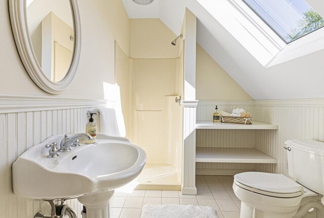 bathroom featuring a shower, lofted ceiling with skylight, tile floors, sink, and toilet