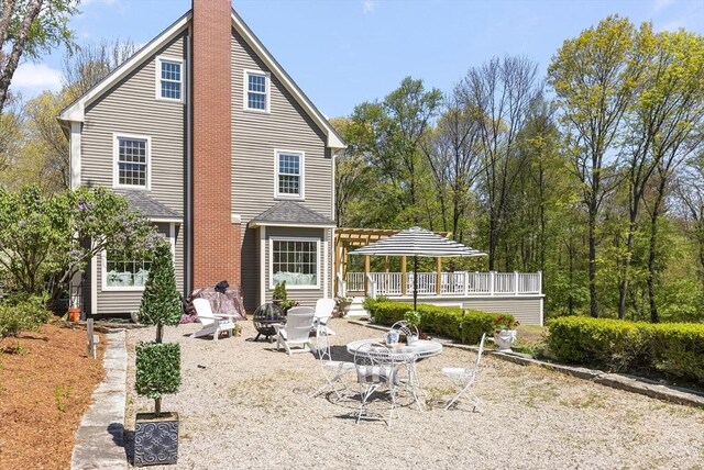 rear view of property with a patio, a pergola, and an outdoor fire pit