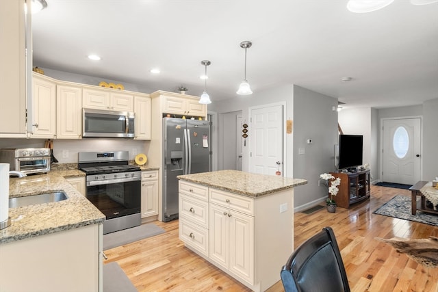 kitchen with light hardwood / wood-style floors, appliances with stainless steel finishes, a center island, and decorative light fixtures