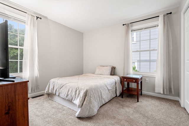 bedroom featuring light colored carpet and multiple windows