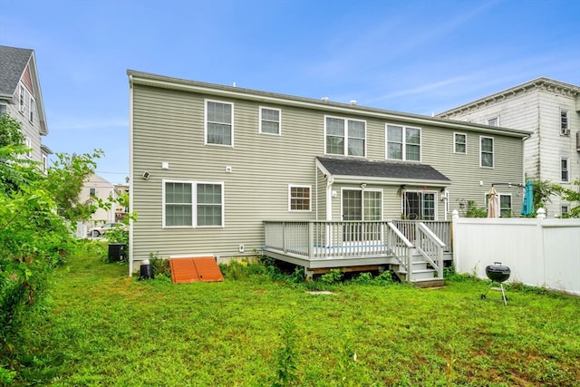 back of property with a deck, a lawn, and central AC unit