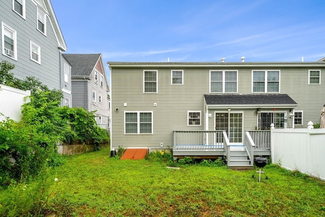 back of property with a deck and a lawn