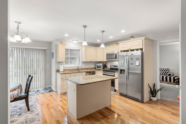 kitchen with appliances with stainless steel finishes, decorative light fixtures, light stone counters, and a center island