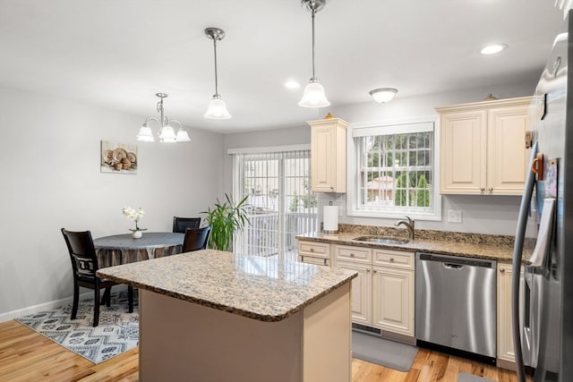 kitchen featuring light wood-type flooring, pendant lighting, sink, dishwasher, and a center island