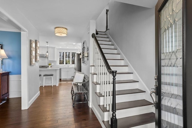 foyer entrance with stairway, baseboards, and dark wood finished floors