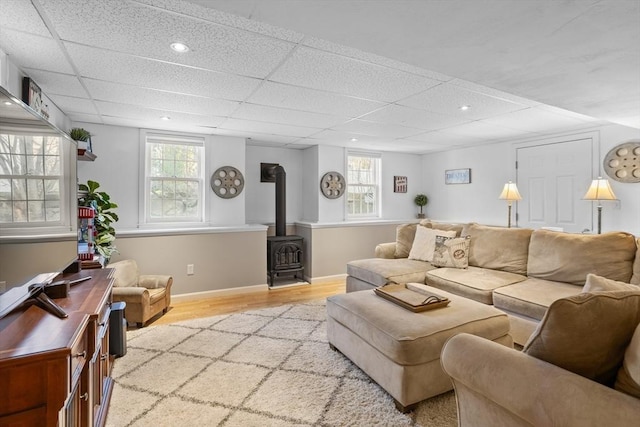 living room featuring light wood-style floors, a wood stove, baseboards, and a wealth of natural light