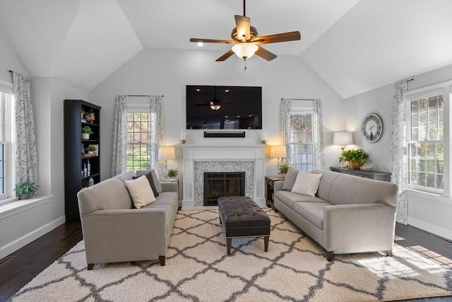 living area featuring ceiling fan, vaulted ceiling, wood finished floors, and a fireplace