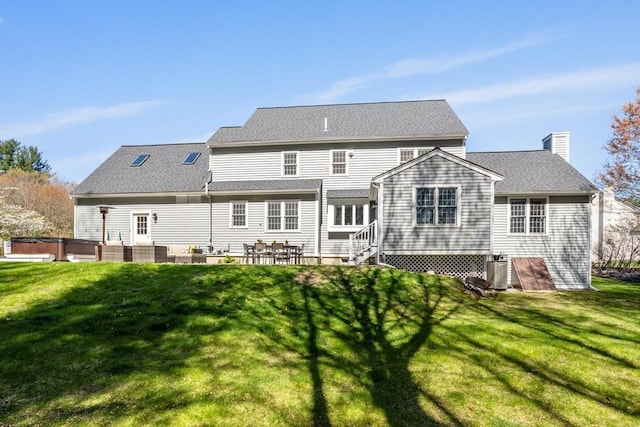 rear view of house with a hot tub, a lawn, central AC, and a patio