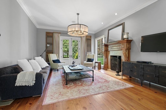 living area with crown molding, a notable chandelier, wood finished floors, and a fireplace