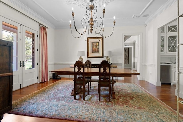 dining space with ornamental molding, wood finished floors, and a notable chandelier